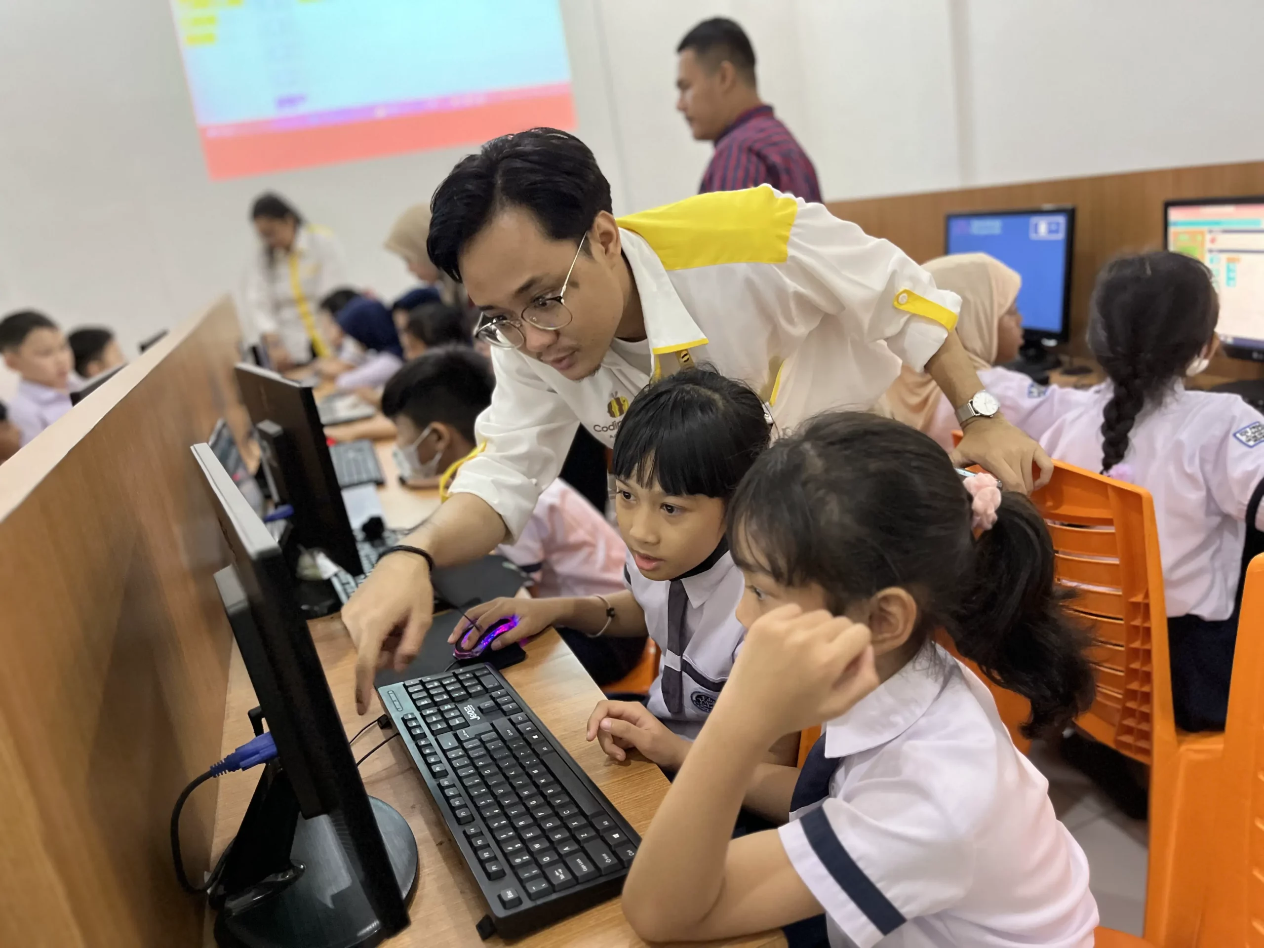 a teacher explaining to kids in front of the computer